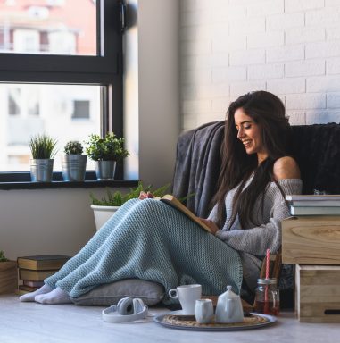 Beautiful young woman reading a bookat home